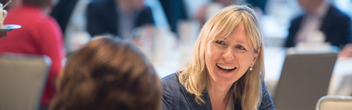 Anne Maggisano speaking with a guest at a Women of Burgundy event