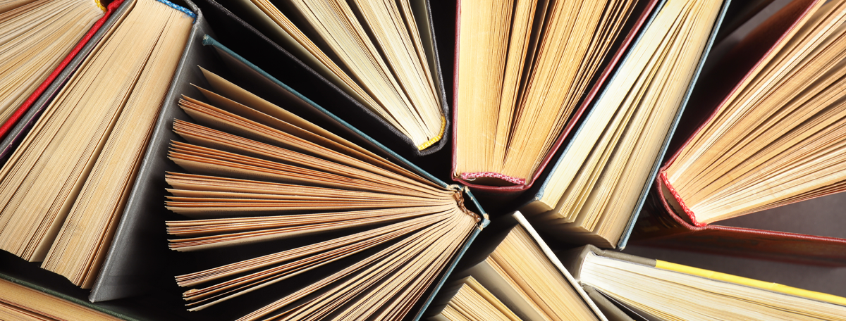 Many different hardcover books on dark background, top view