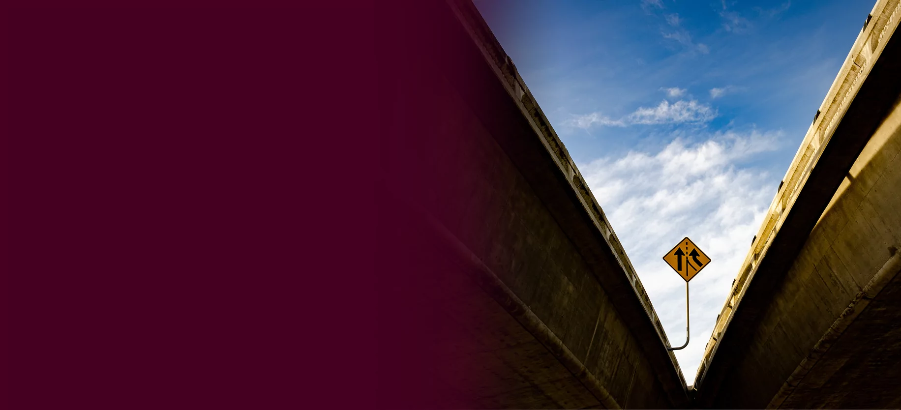 A merge sign on an overpass