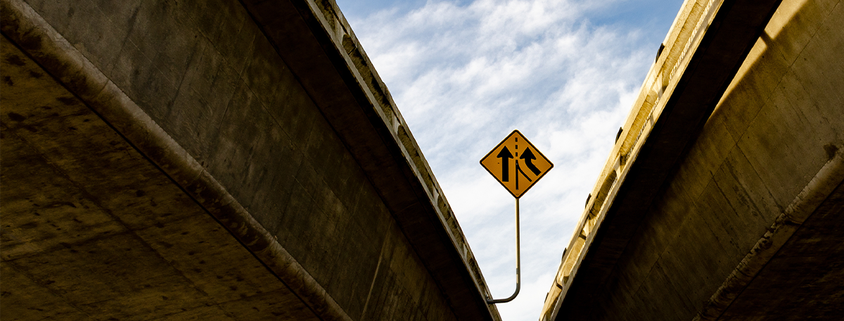 A merge sign on an overpass