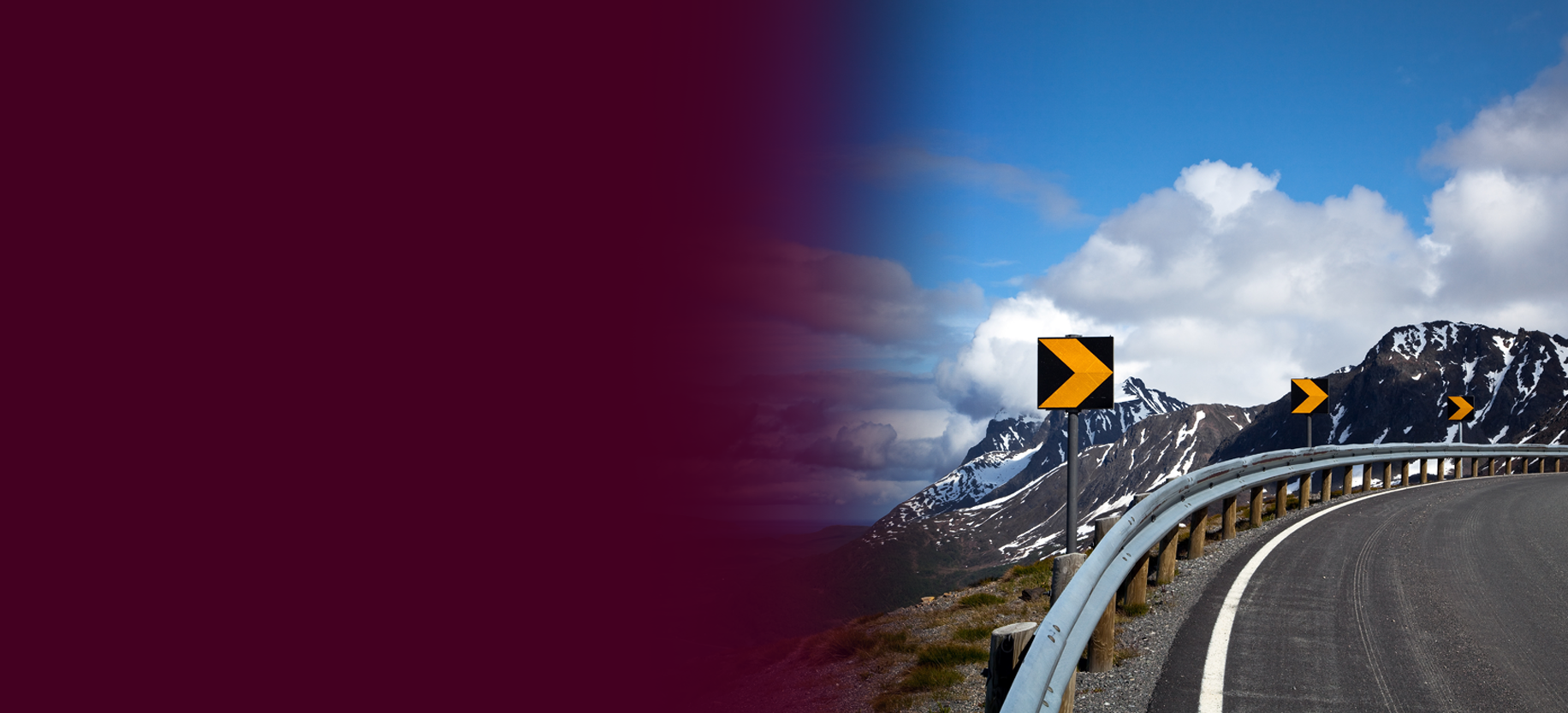 Traffic signs along a road barrier overlooking a mountain range