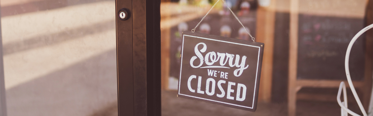 A sign in a storefront window that reads "sorry we're closed"