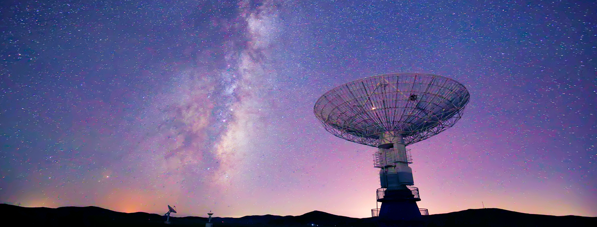 Radar dish pointed towards a night sky that is full of stars