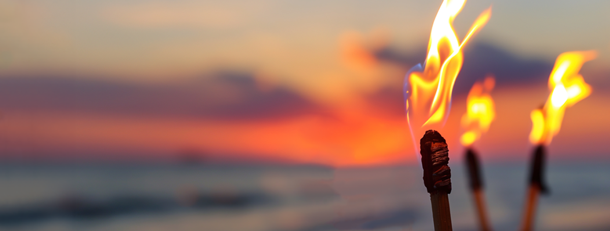 Tiki torches burning on a beach at sunset