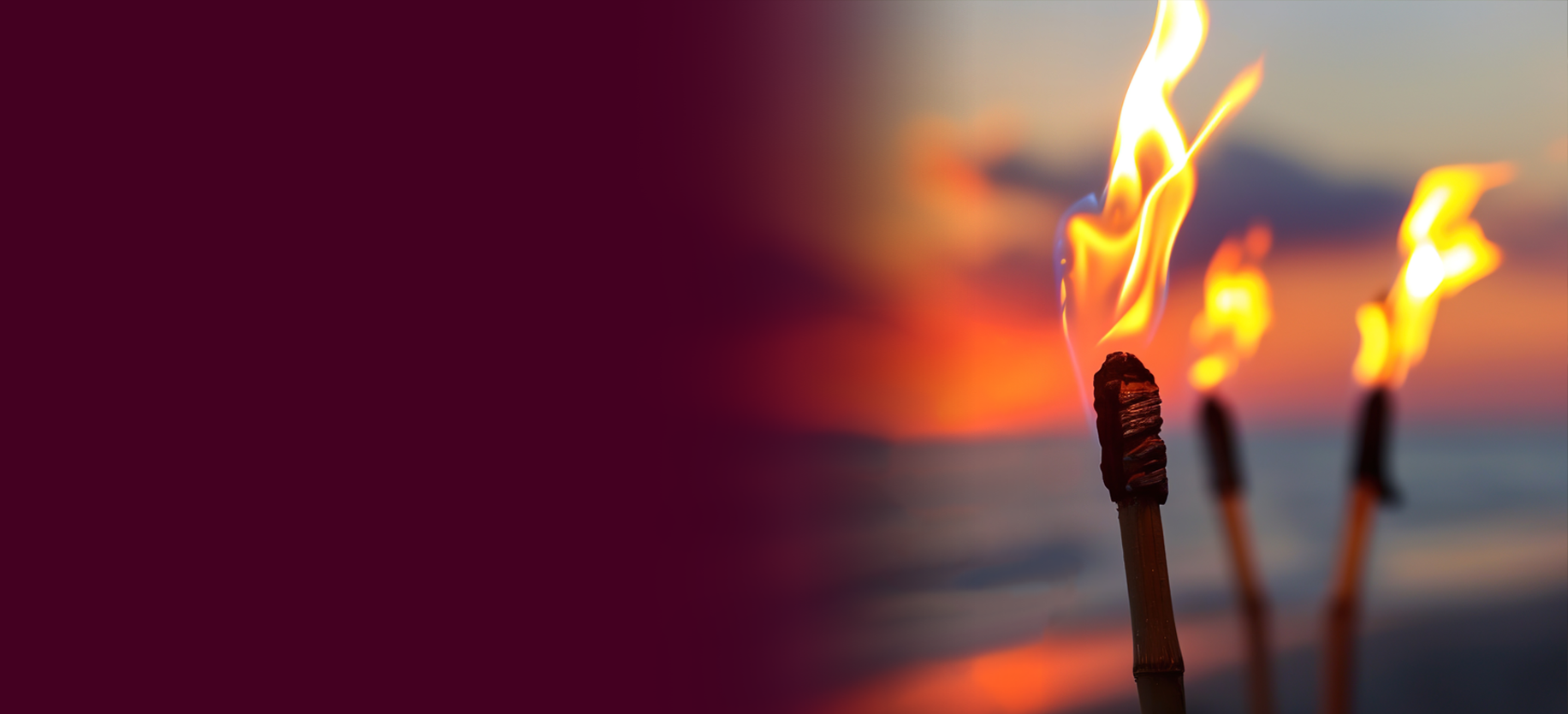 Tiki torches burning on a beach at sunset