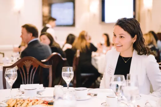 Roz McLean sits at a table speaking with clients at a Montreal Women of Burgundy event