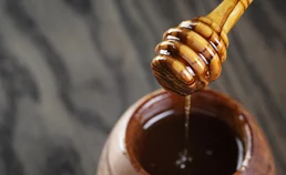 Honey dripping into a honey pot